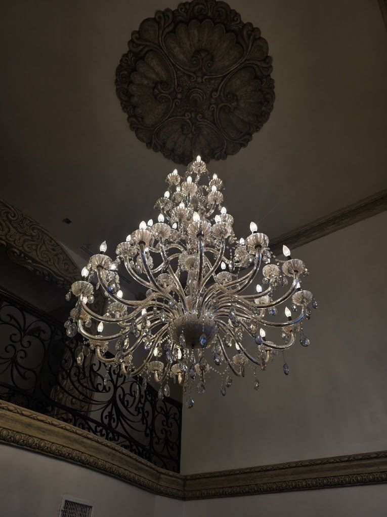 Candelabro de cristal bajo un medallón de techo tallado
