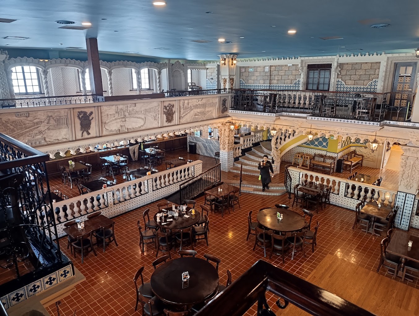 Vista del salón principal desde el mezzanine, con mesas y balcones ornamentados