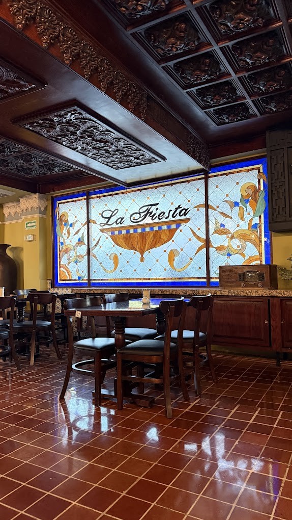 Vitral original con el nombre La Fiesta, bajo el techo tallado del salón
